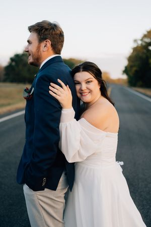 A sweet moment between newlyweds posing on an empty road during their wedding photoshoot.