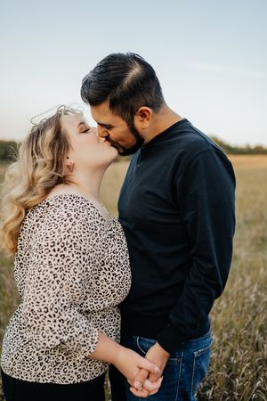 A tender moment between a couple sharing an intimate kiss in a golden field.