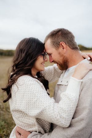 Couple in cozy winter sweaters sharing intimate moment outdoors.