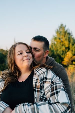 Couple sharing intimate moment outdoors during autumn golden hour photography session.