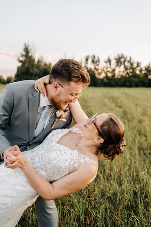 Romantic dip pose during wedding photoshoot in sunset meadow.