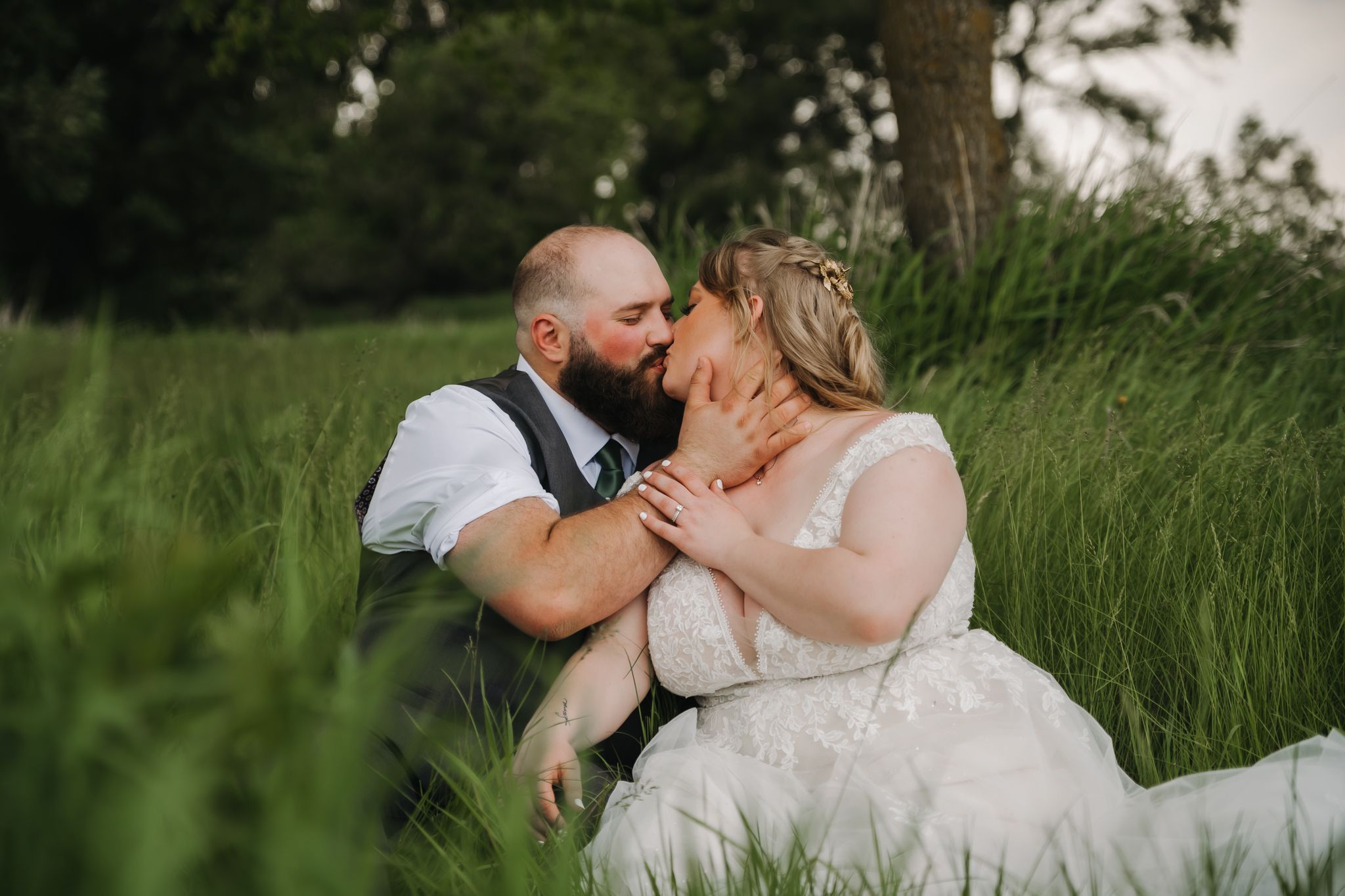 Romantic wedding couple embracing in a lush green field during their outdoor photo session.