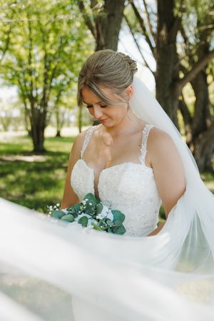 Delicate lace wedding dress details and flowing veil captured in natural outdoor lighting.