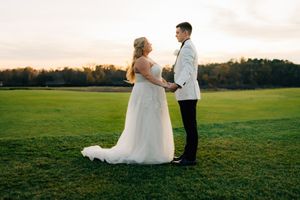 Sunset wedding portrait of couple standing together in an open field.