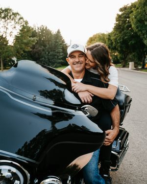 Romantic motorcycle engagement photos at sunset with sleek black bike.