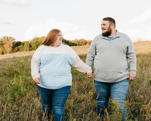 Casual engagement photos in a natural field setting during golden hour.
