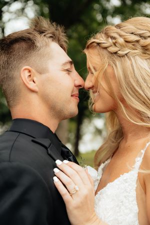 An intimate wedding portrait showing a tender moment between newlyweds outdoors.