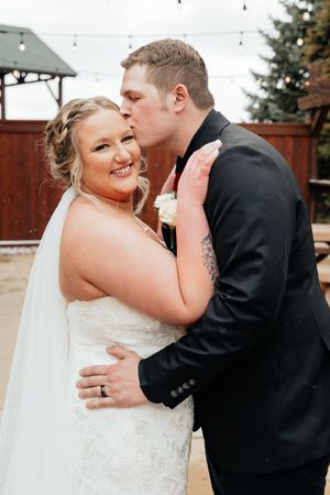 Intimate outdoor wedding portrait of couple sharing tender moment against wooden fence.