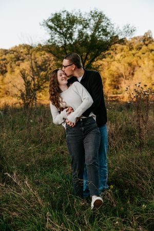 Couple sharing a tender moment in a golden field during sunset.