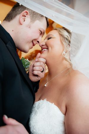 Close-up shot of a joyful wedding couple sharing an intimate moment under a veil.