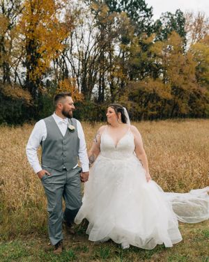 A romantic autumn wedding photoshoot in a golden field with flowing white dress and gray vest attire.