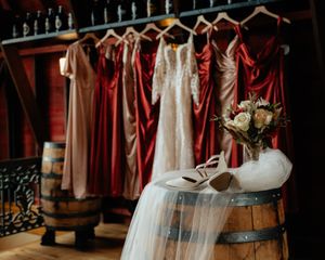 Wedding dresses and burgundy bridesmaid gowns hang on display racks in a bridal boutique.