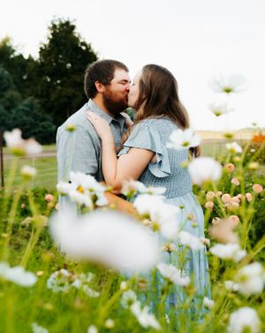 Romantic couple embracing among white wildflowers in a summer meadow.