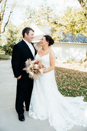Joyful wedding couple shares candid laughing moments during outdoor fall photo session.
