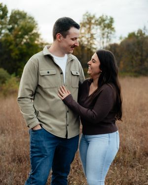 A couple shares an intimate moment while standing together in a golden autumn field at sunset.
