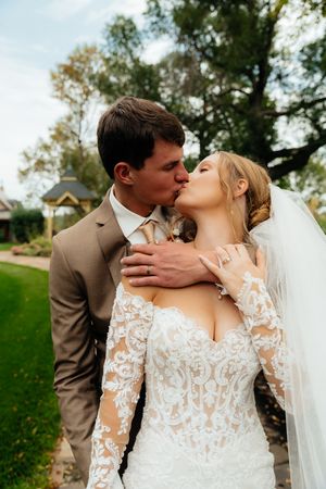 A romantic wedding moment captured outdoors with a beautiful lace dress and tan suit.