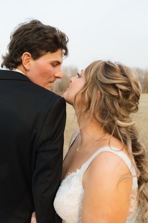 A romantic wedding photo of a couple sharing an intimate moment, with the bride in a lace strap dress.