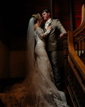 A romantic moment captured in a dimly lit indoor setting with elegant decor and wooden details.