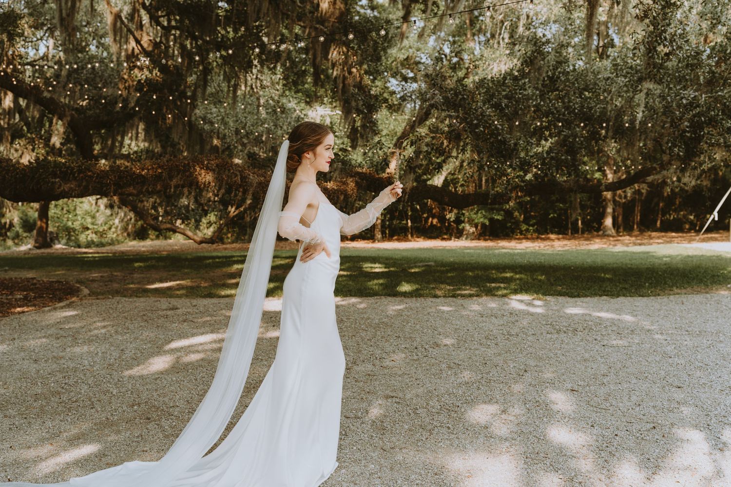 Outdoor wedding ceremony setup with white chairs on grass under trees.