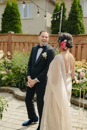 A wedding ceremony in a backyard garden with string lights and a decorated floral arch.