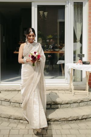 An elegant wedding celebration on a stone patio outside a glass door entrance.