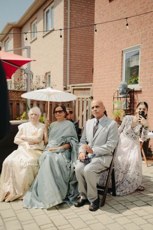 Wedding guests seated outdoors under string lights and umbrellas during a backyard celebration.