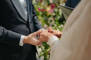 Close-up of hands exchanging rings during an outdoor wedding ceremony.