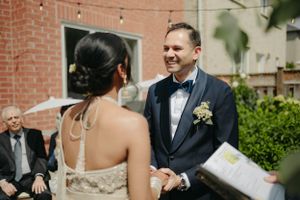 An intimate outdoor wedding ceremony moment under string lights and greenery.