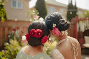 Two elegant hairstyles adorned with red flowers photographed from behind.