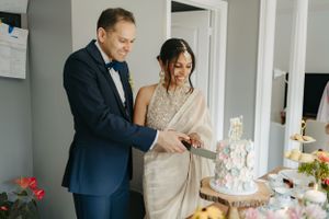 A couple admires their elegant white wedding cake together at their reception.