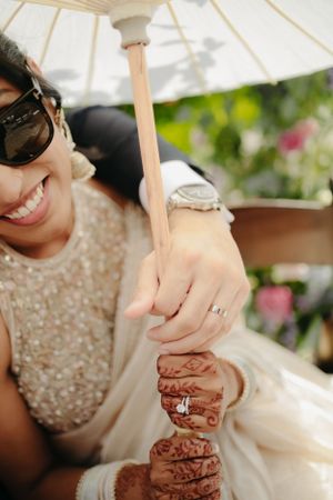 Close-up of intricate henna designs on hands with an engagement ring.