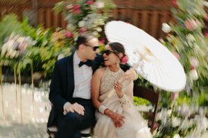 A romantic moment under a white parasol surrounded by garden flowers.