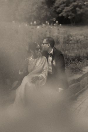 A dreamy black and white photo of a couple sitting in a misty garden.