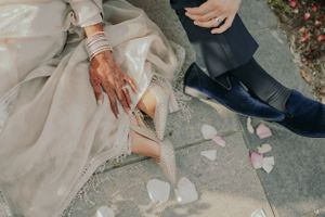 Detail shot of wedding couple's feet with rose petals scattered on stone ground.