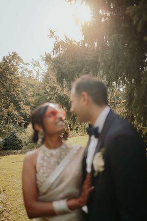A tender sunlit wedding moment captured between newlyweds in an outdoor garden setting.