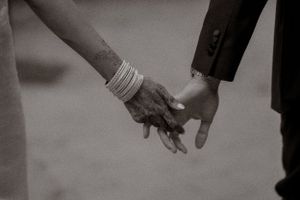 An intimate black and white photo of two hands joining together in a romantic gesture.