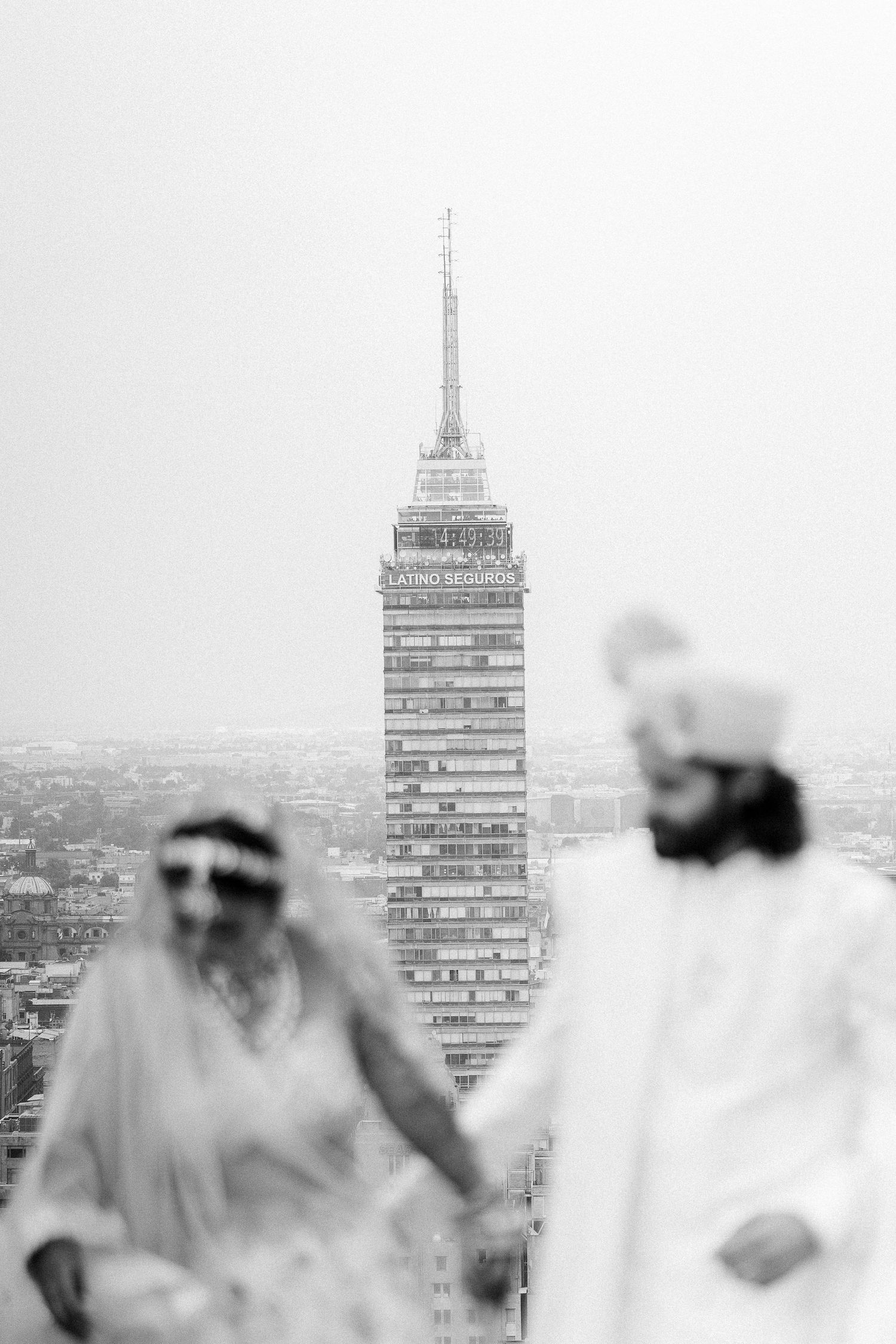 Black and white cityscape with tall buildings visible through a soft focus foreground.
