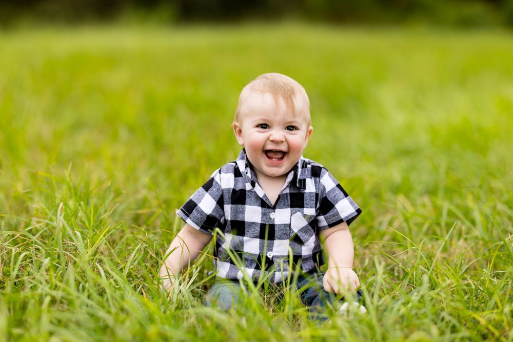 Happy baby laughing while playing on green grass outdoors.