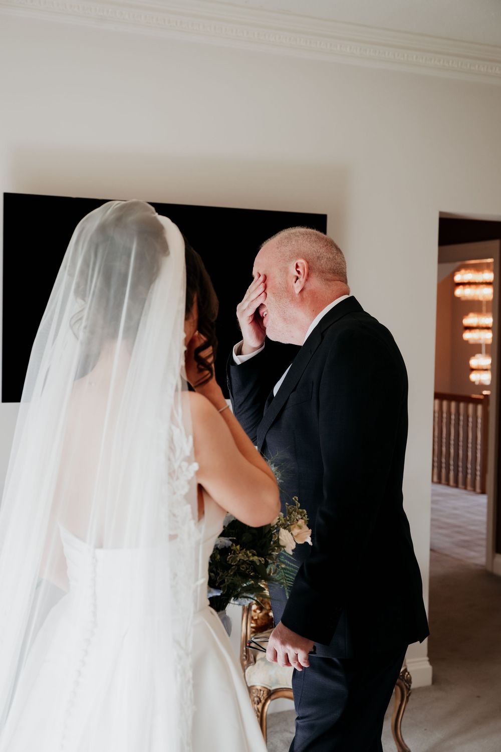 Father of bride emotional reaction during first look moment with daughter in wedding gown and veil.