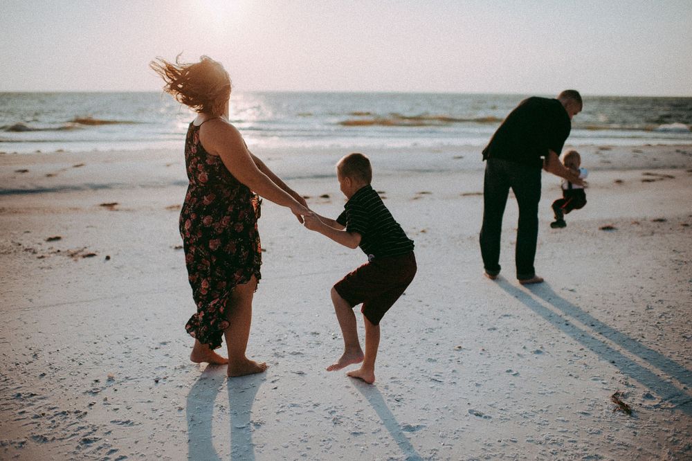 People walking along a sandy beach at sunset while collecting seashells and enjoying the ocean waves.