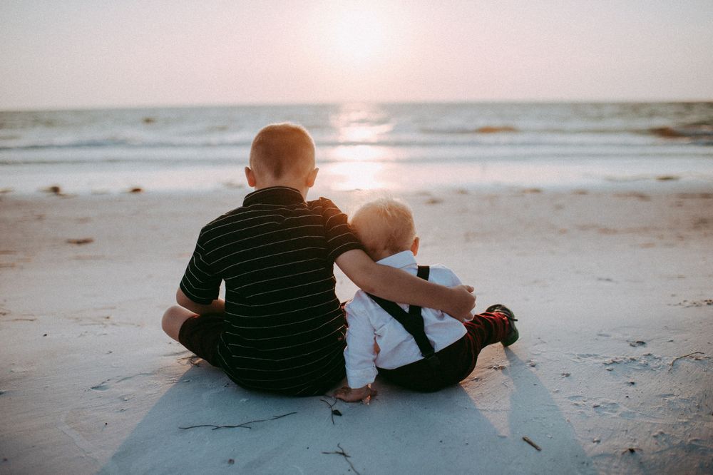 A series of beach photos showing people sitting together on the sand at sunset watching the waves roll in.