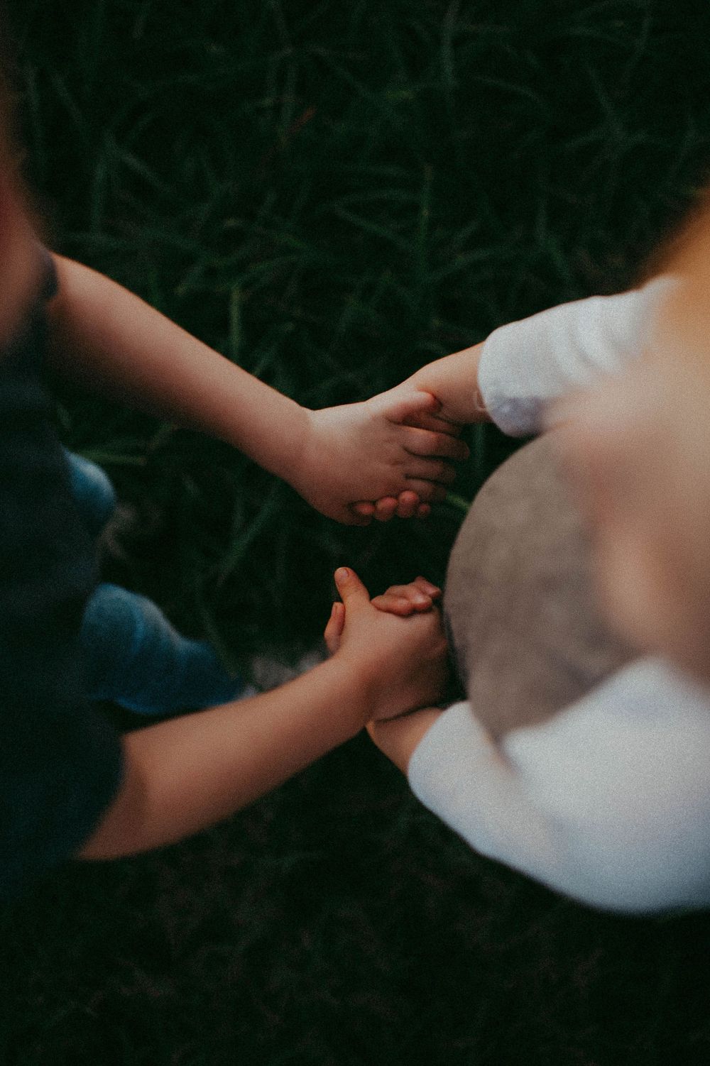 Close-up of hands joining together in a dark, atmospheric setting. Sarasota Family Photographer. Lido Beach Photographer.