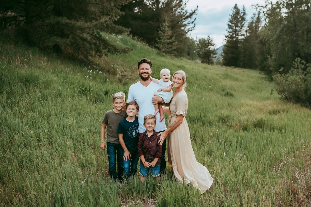 Family portrait on green hillside with pine trees in background. Sarasota Family Photographer. Lido Beach Photographer.