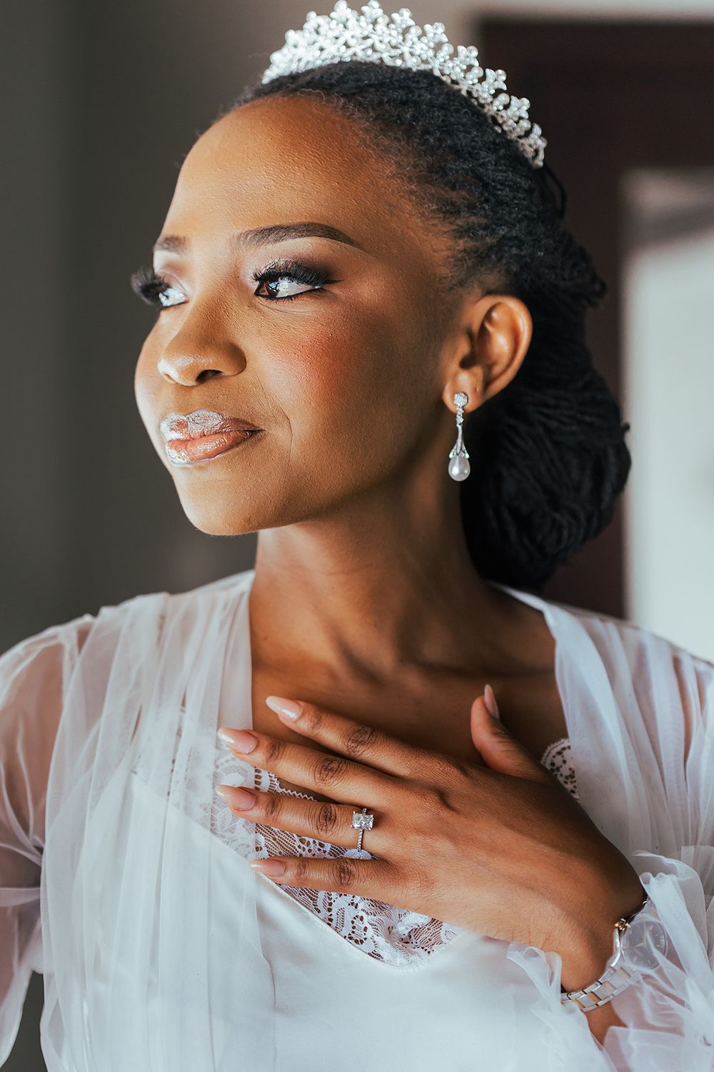 Close up portrait of bride wearing sparkling tiara and elegant drop earrings.