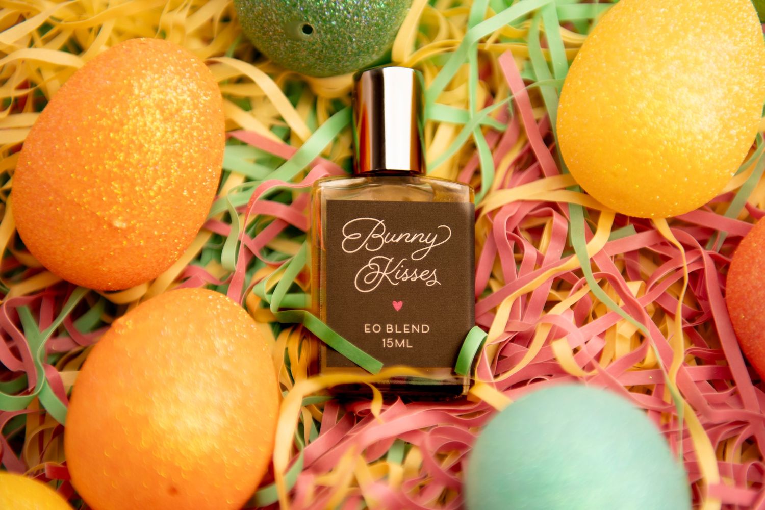 A brown perfume bottle nestled among colorful Easter eggs and pastel paper grass decorations.
