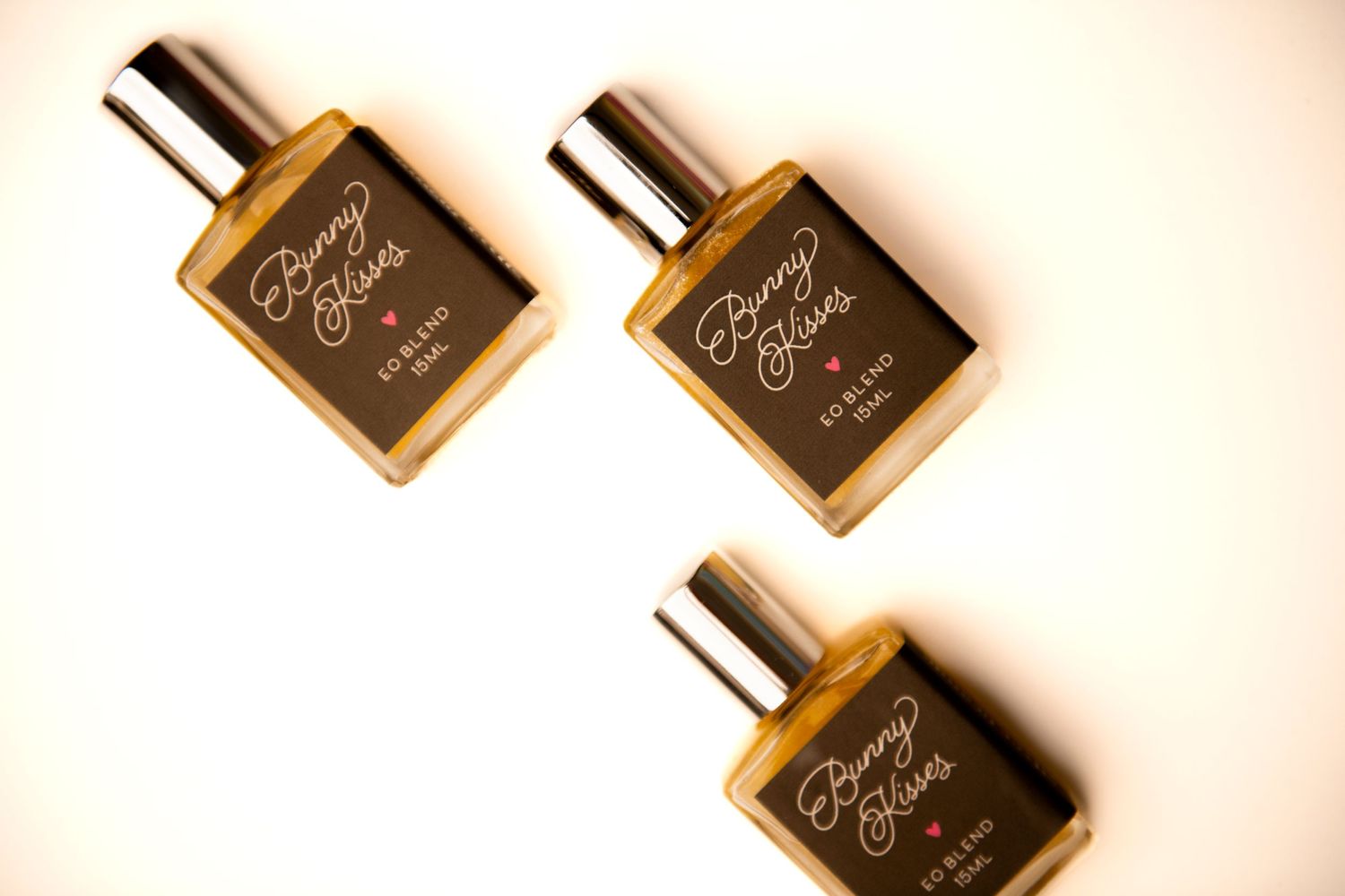 Three identical amber glass perfume bottles with black labels arranged diagonally on a white background.