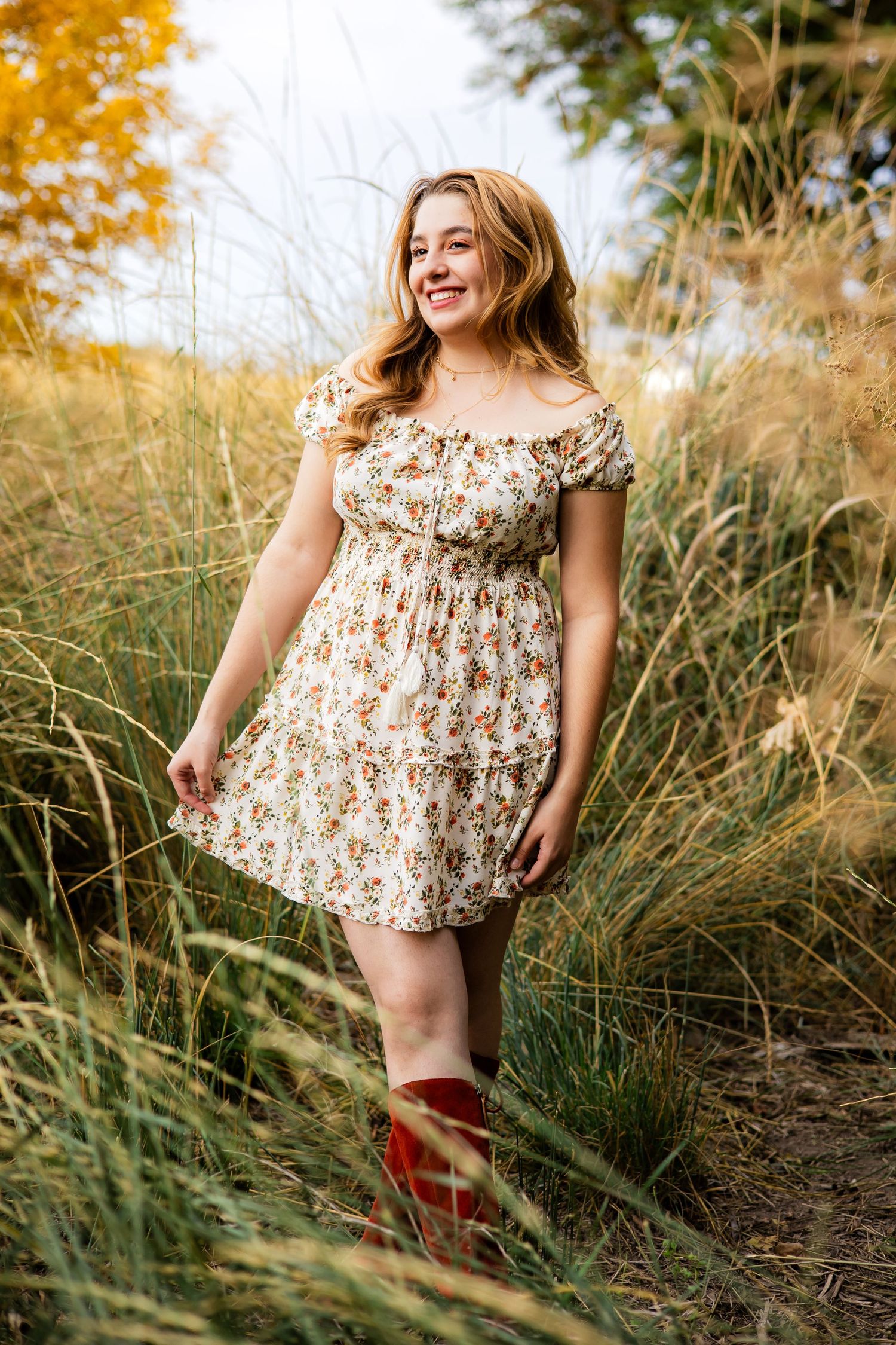 A high school senior holding the edge of her dress while smiling away from the camera