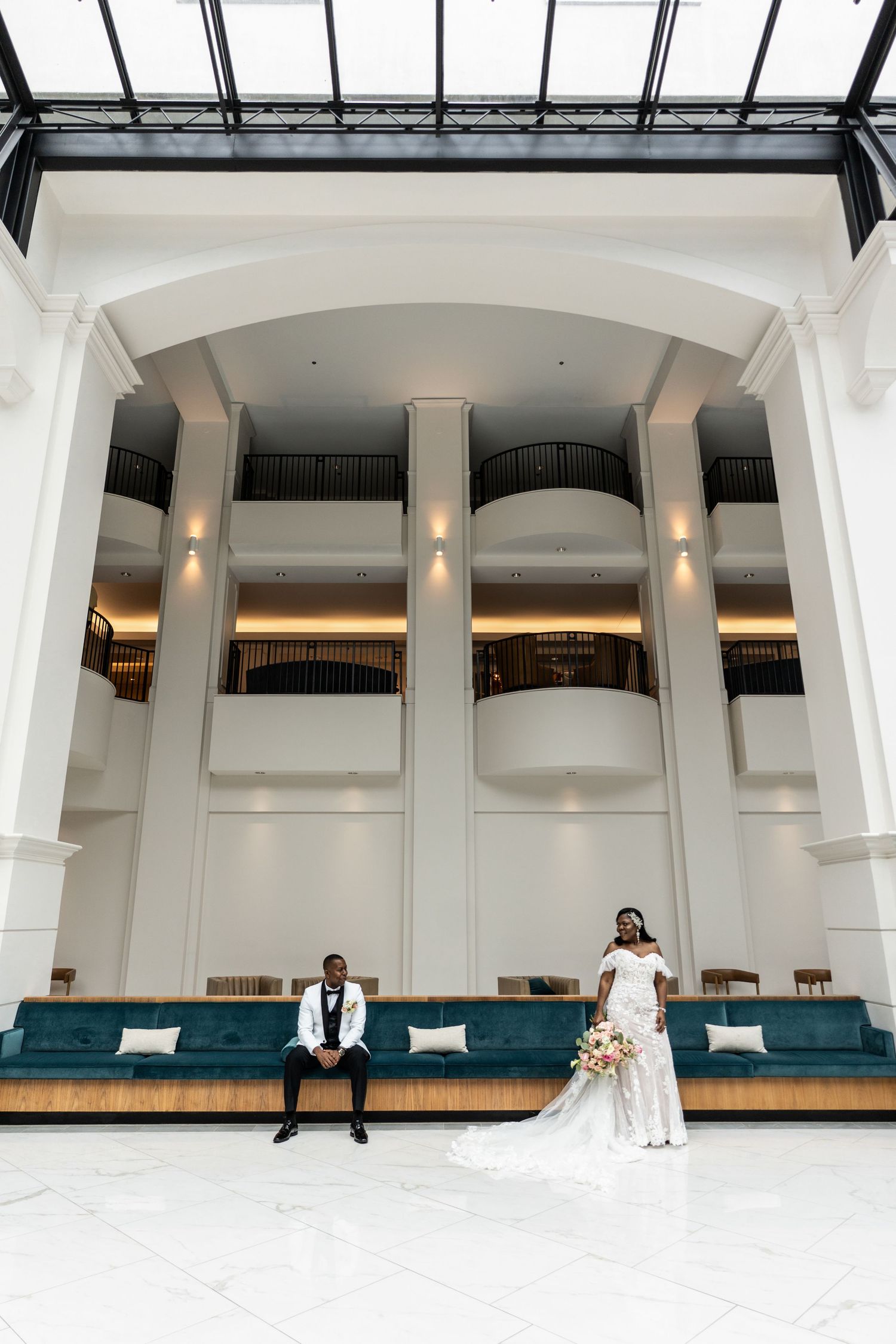 Wedding party celebrates on grand stone building steps with classic columns and decorative planters.