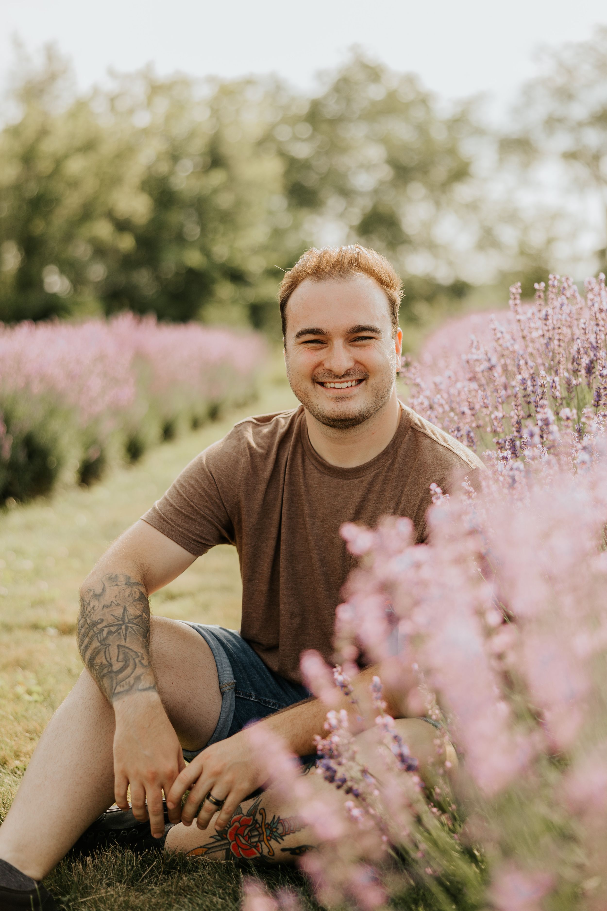 Person sitting among blooming purple wildflowers in summer field.