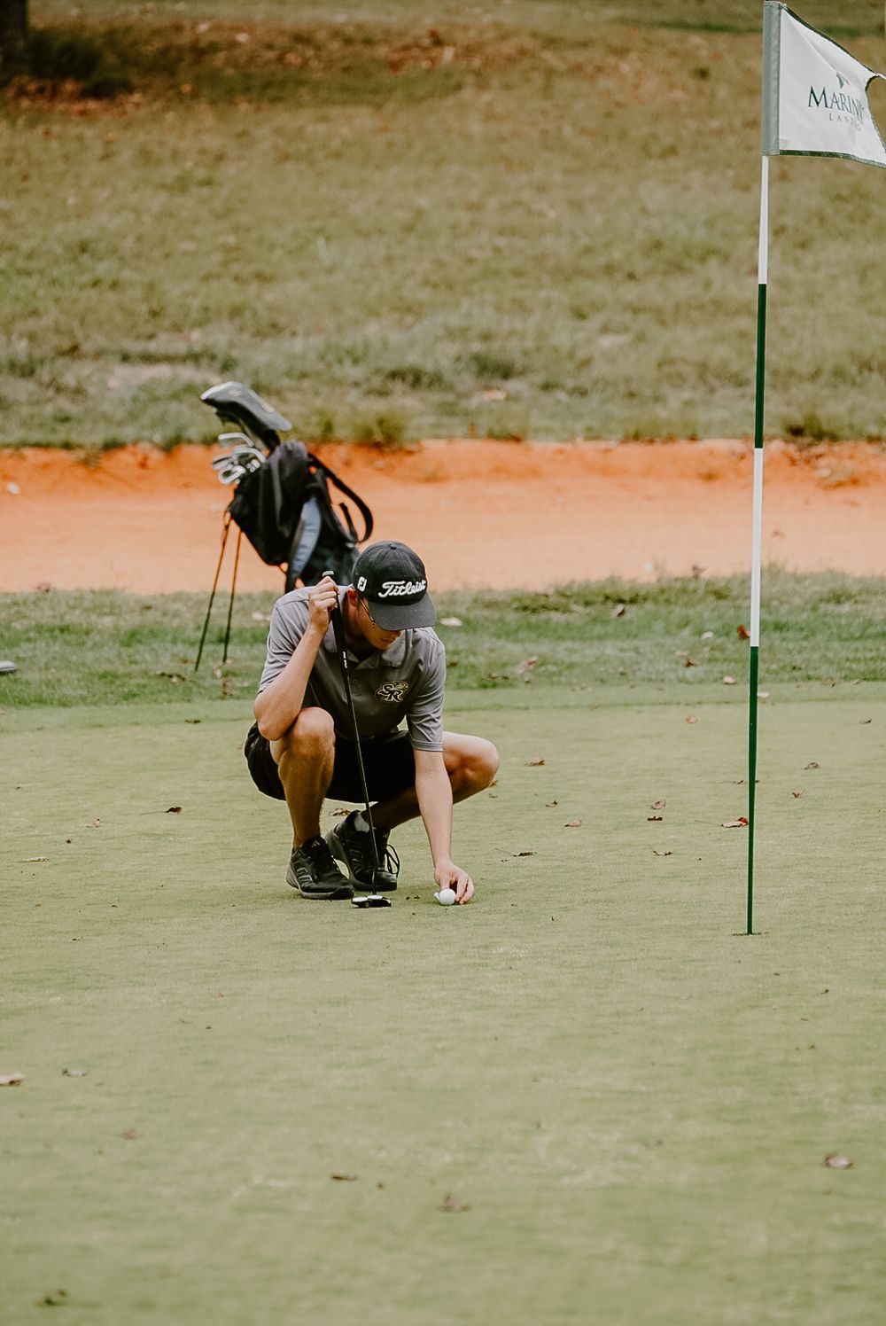 Photographer lying on golf green taking low angle shot near flag.